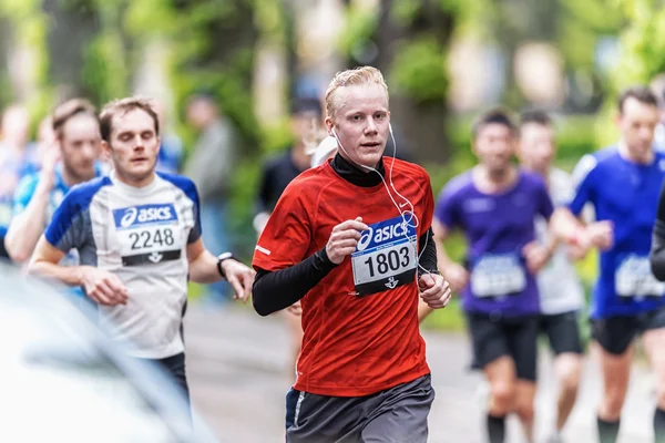 Running man in red in a lush area at ASICS Stockholm Marathon — Stok fotoğraf