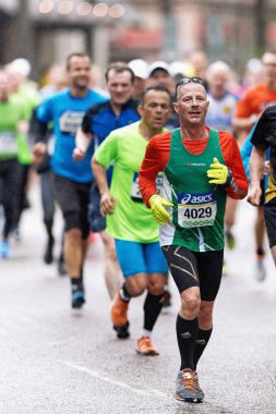 Running man in green at the streets of Stockholm at ASICS Stockh