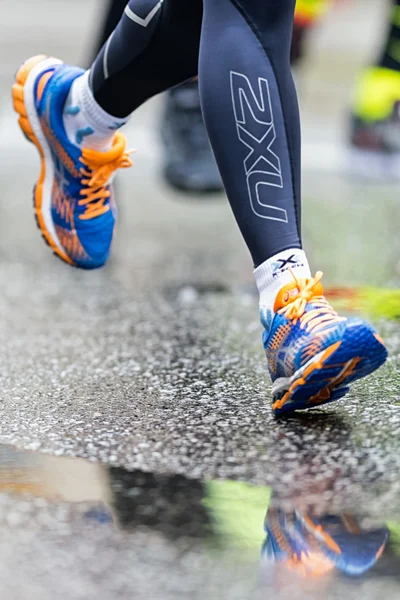 Colorful running shoes reflecting in puddles at the wet street