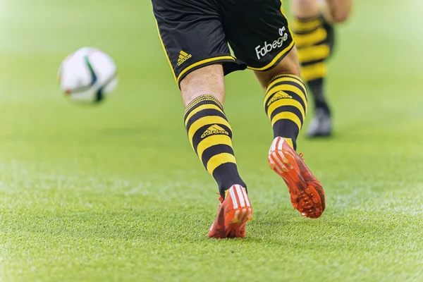 Soccer players legs and shoes aiming at the football during warm
