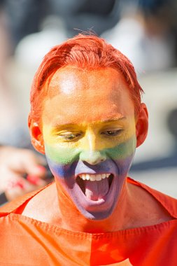 Rainbow colors painted on face of a man at the Pride parade