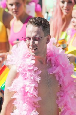 Bare chested man with pink boa and eyelashes at the Pride parade