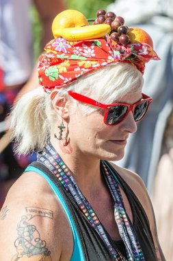 Blonde woman with fruits on head giving away neckbands at the Pr