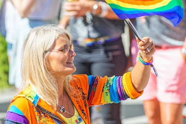 Blond woman in colorful clothes waving the rainbow flag at the P — Stok fotoğraf