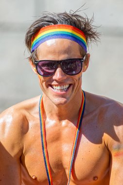 Fit man with rainbow colors on a floater at the Pride parade