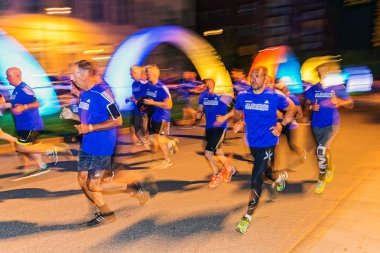 Runners in colorful lights on the streets of Soder at Midnattslo