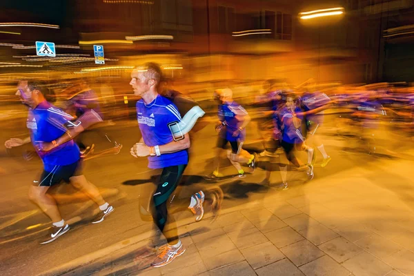 Male runners in motion blur and colorful light trails on the str