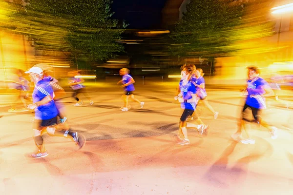 Läufer in Bewegung verschwimmen und bunte Lichtschilder auf den Straßen — Stockfoto