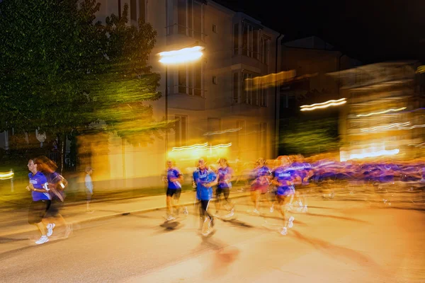 Läufer in Bewegung verschwimmen und bunte Lichtschilder auf den Straßen — Stockfoto