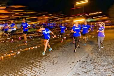 Runners at a water station with motion blur on the streets of So