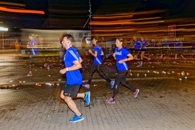 Three runners passing by a water station with motion blur on the