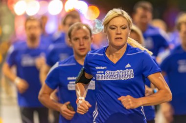 Female runner in colorful yellow street light at Midnattsloppet 