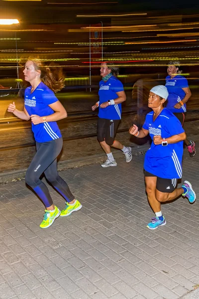 Four women running with motion blur on the streets of Soder at M — стокове фото