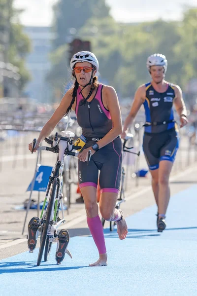 Female triathletes running with bike and shoes in the transition — Stock Photo, Image