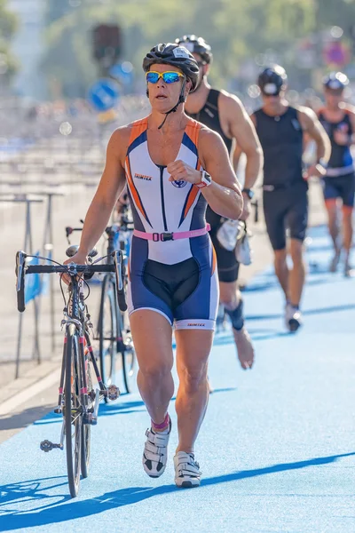 Male triathletes running with bike and shoes in the transition a — Stock fotografie