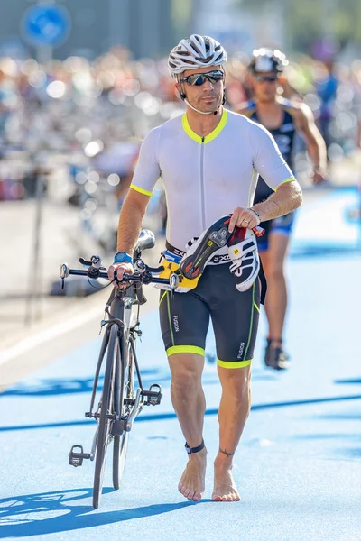 Triathlete running with bike and shoes in the transition area th — Stok fotoğraf