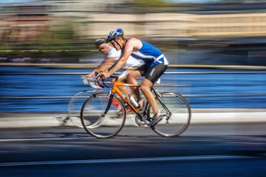 Two colorful triathletes cycling with motion blur of the panning