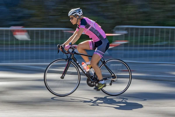 Female triathlete in pink cycling with motion blur of the pannin — Stockfoto