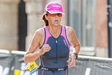 Woman triathlete running at the cobblestones in the old town at