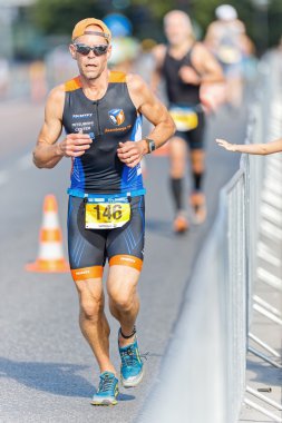 Triathlete running on asphalt with a kids hand cheering on at IT