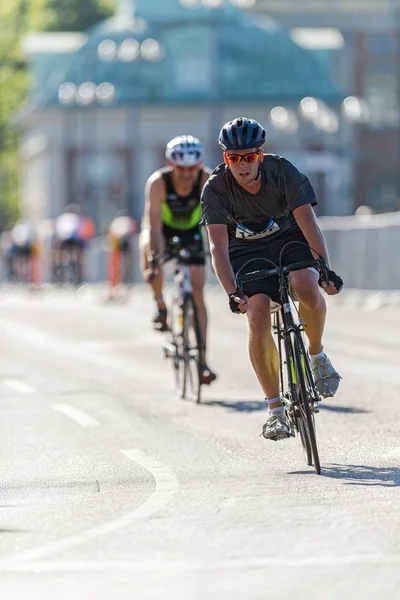 Male triathlete in standard clothes taking a curve at the old to — Zdjęcie stockowe