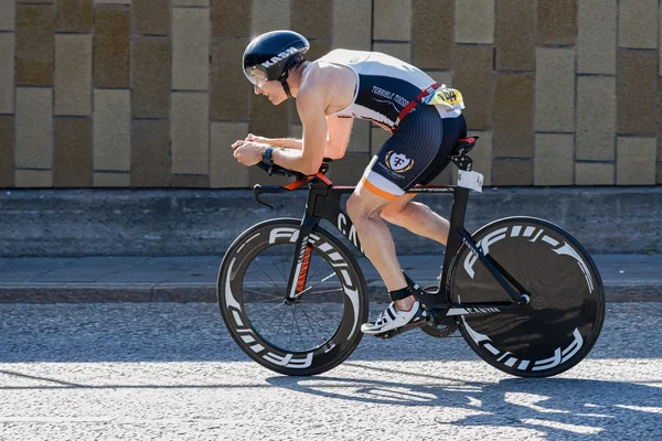 Triathlete cycling with a speedy bike in partial sunlight at the — Stockfoto