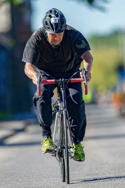 Older amateur triathlete cyclist in front view at the ITU World — Stok fotoğraf