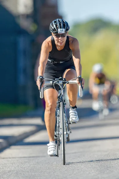 Female triathlete in black on the bike at the ITU World Triathlo — Zdjęcie stockowe