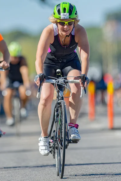 Female triathlete in green helmet on the bike at the ITU World T — Stok fotoğraf