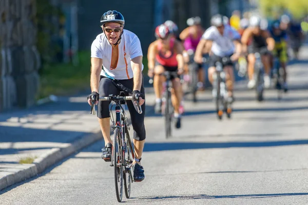 Grupo de triatletas con un hombre mayor delante en la bicicleta en th —  Fotos de Stock