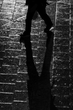 Yüksek karşıtlık içinde uzun gölgeler ile yürüyen kişi