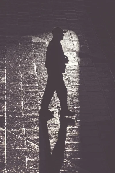 Прогулянка людини з довгими тінями у високому контрасті — стокове фото