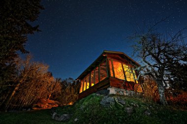 Turuncu windows ve bir yıldızlı gece gökyüzü ile ev