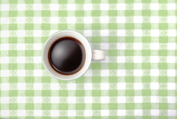 Top view of black coffee mug on checked tablecloth in green — Stock Photo, Image