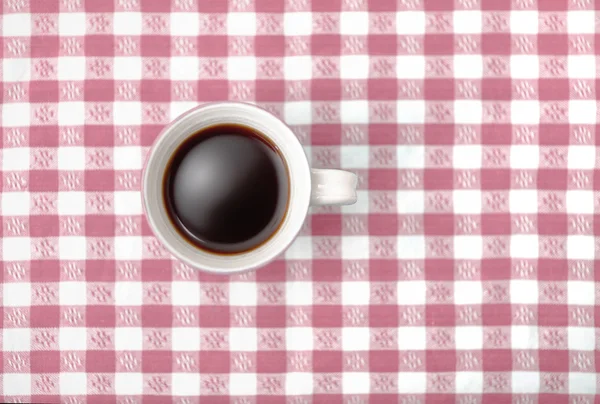 Top view of black coffee mug on checked tablecloth in red — Stock Photo, Image