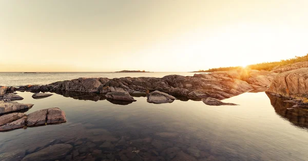 Sunrays over rocky coast during early morning — Stock Photo, Image