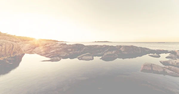 早朝の間に明るいの岩石の多い海岸の上の日差し — ストック写真
