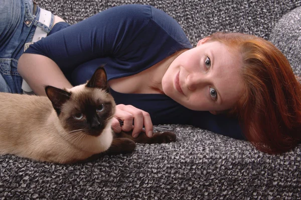 Молода жінка з сиамським котом — стокове фото