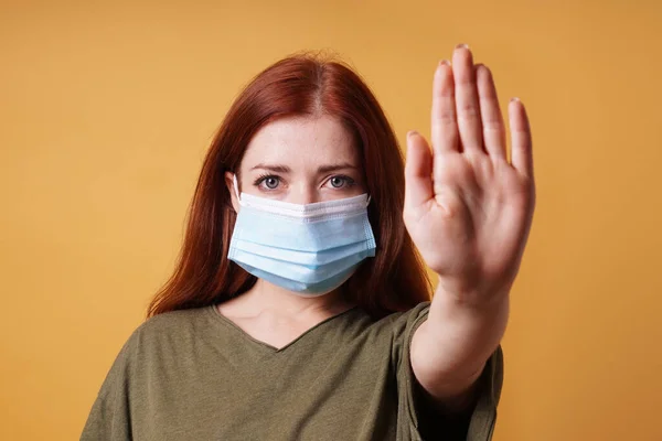 young woman wearing medical face mask making stop hand gesture