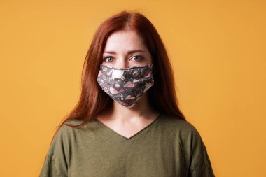 Ev yapımı bez yüz maskesi ya da toplum maskesi takan genç bir kadın
