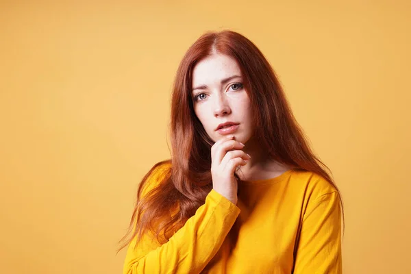 Thoughtful young woman with finger on chin gesture — Stock Photo, Image