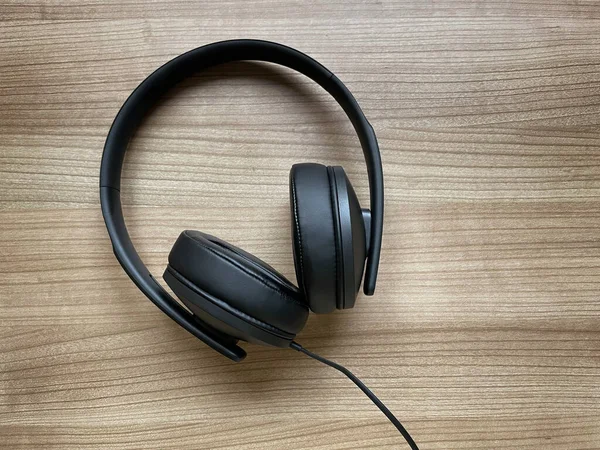 Schwarze Rund-um-das-Ohr-Kopfhörer liegen auf Holztisch — Stockfoto