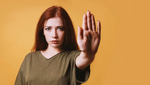 Серьезная молодая женщина делает стоп-жест левой рукой — стоковое фото