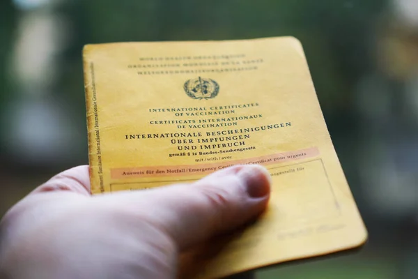 Mano en posesión de certificados internacionales de vacunación o Impfbuch en alemán —  Fotos de Stock
