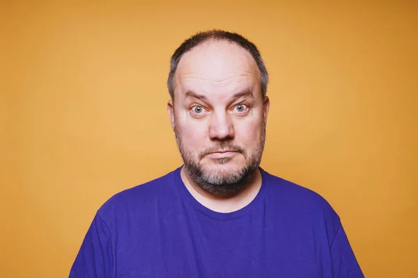 Hombre adulto medio con mirada estupefacta en su cara contra fondo de estudio de color naranja — Foto de Stock