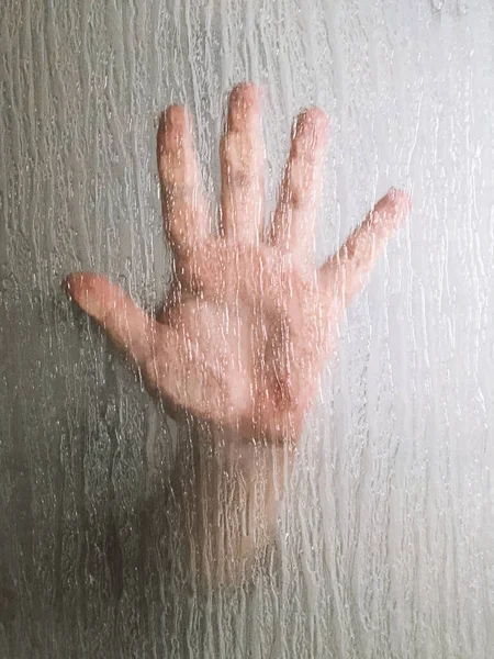 Main derrière fenêtre en verre givré — Photo
