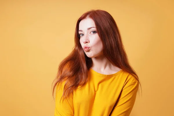 Jovem mulher puckering seus lábios para um beijo ou rosto de pato expressão facial — Fotografia de Stock