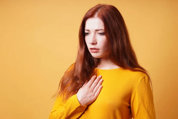 Sad young woman with hand on chest feeling heartache or heartburn — Stock Photo, Image