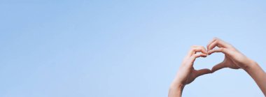 Kadın elleri kalp şeklinde işaret ya da gökyüzüne karşı sevgi hareketi yapıyor