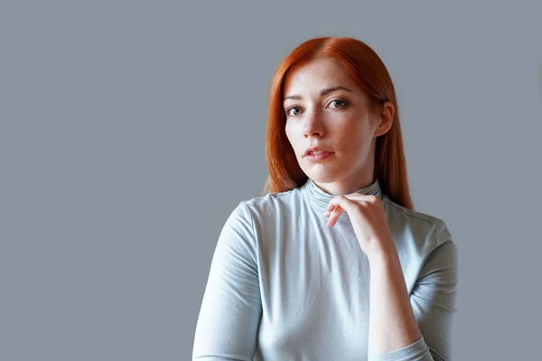 Jovem contemplativa com cabelo vermelho longo e gola alta azul claro — Fotografia de Stock